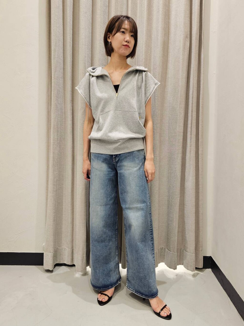 ブラック系のスリッポン、ブルー系のデニムパンツ、グレー系のパーカーを着用したレディースの夏コーディネートの2枚目の写真