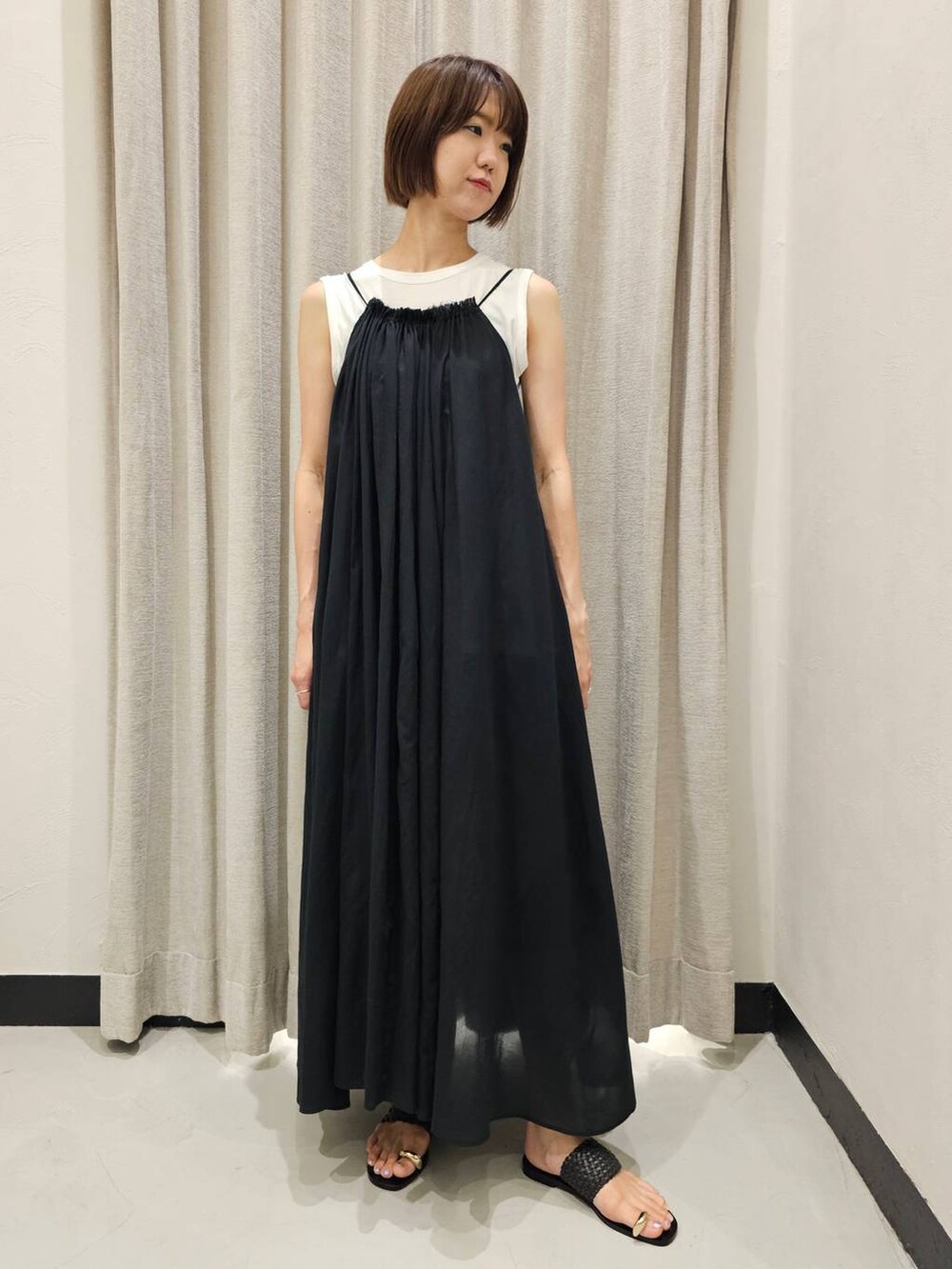 ブラック系のサンダル、ブラック系のワンピース、ホワイト系のTシャツ/カットソーを着用したレディースの夏コーディネートの2枚目の写真