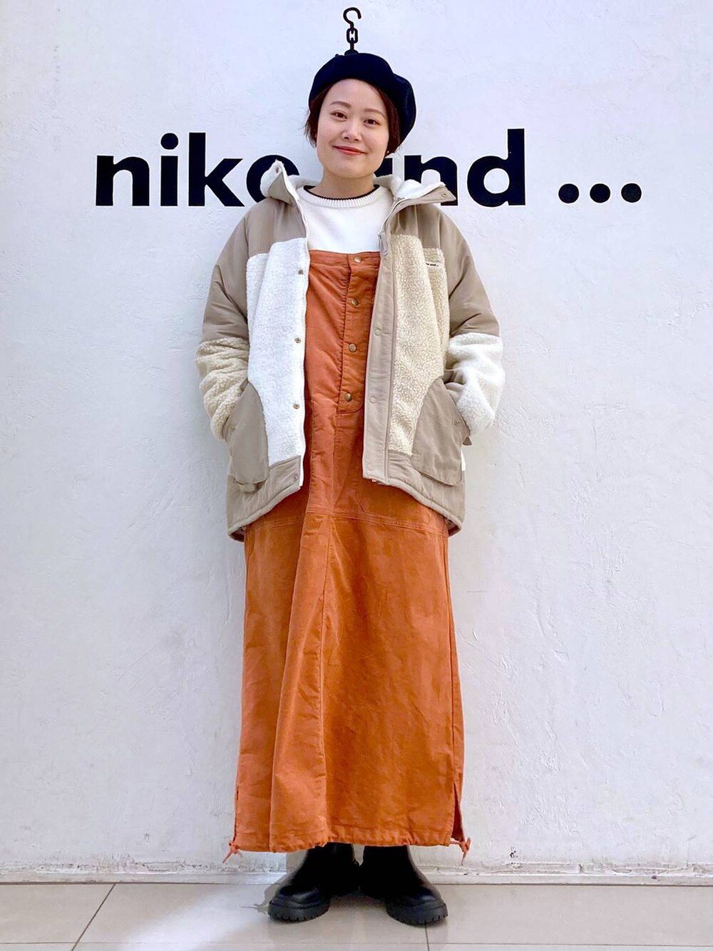 ベージュ系のその他アウター、ホワイト系のニット/セーター、ブラック系のブーツを着用したレディースの冬コーディネートの5枚目の写真