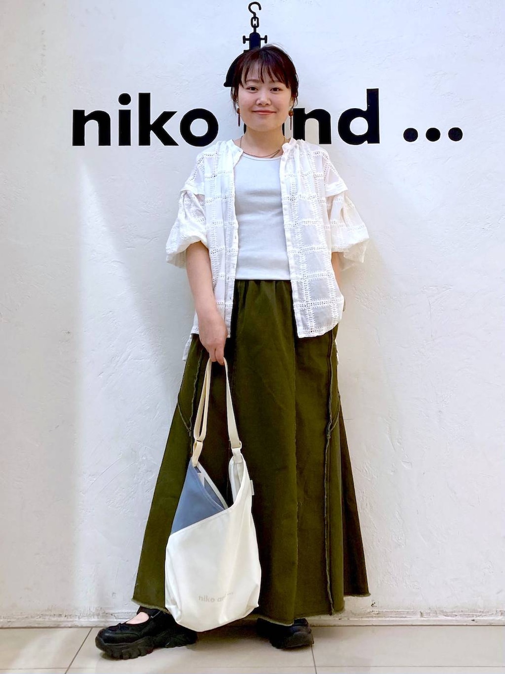 グレー系のタンクトップ、ベージュ系のトートバッグ、ブラック系のスニーカーを着用したレディースの春コーディネートの2枚目の写真