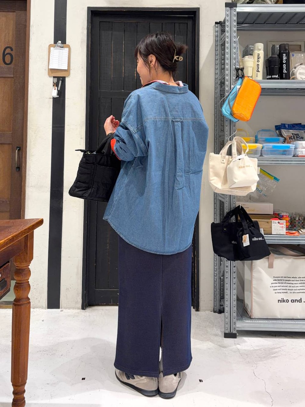 ブラック系のトートバッグ、ブルー系のスカート、その他のネックレスを着用したレディースの春コーディネートの4枚目の写真