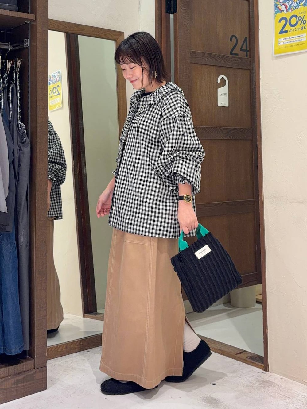 イエロー系のスカート、ブラック系のパンプス、ブラック系のトートバッグを着用したレディースの春コーディネートの4枚目の写真