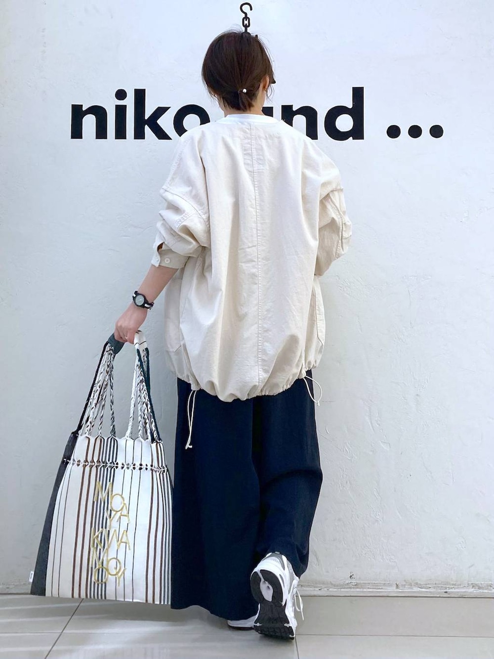 ホワイト系のTシャツ/カットソー、ブラック系のトートバッグ、ベージュ系のブルゾンを着用したレディースの春コーディネートの5枚目の写真