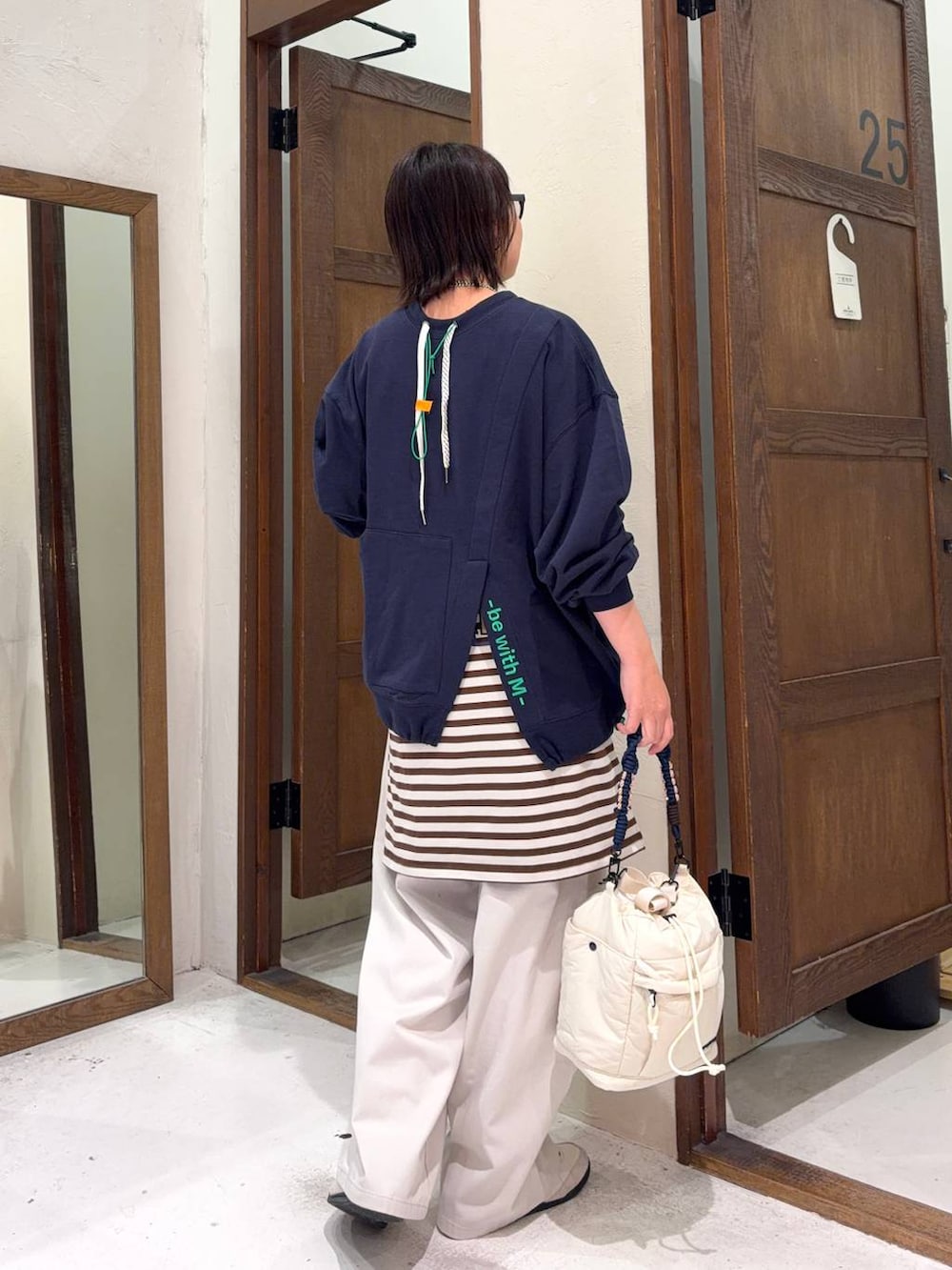 ベージュ系のチノパンツ、ベージュ系のショルダーバッグ、ブラウン系のサングラスを着用したレディースの冬コーディネートの3枚目の写真