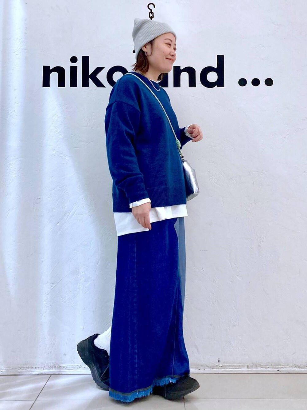 シルバー系のショルダーバッグ、ブルー系のデニムスカート、ブルー系のニット/セーターを着用したレディースの冬コーディネートの5枚目の写真