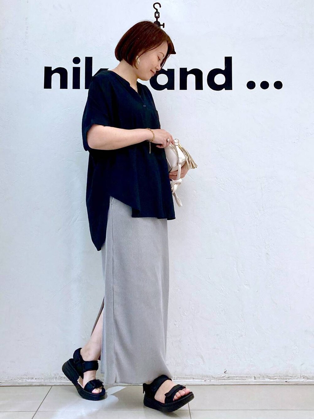 ブラック系のサンダル、ホワイト系のタンクトップ、ブラウン系のショルダーバッグを着用したレディースの夏コーディネートの3枚目の写真