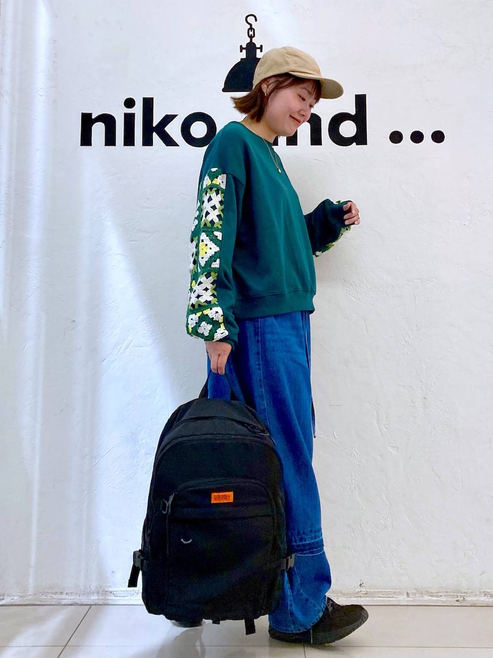 グリーン系のスウェット、ブルー系のデニムパンツ、ブラック系のバックパック/リュックを着用したレディースの秋コーディネートの5枚目の写真