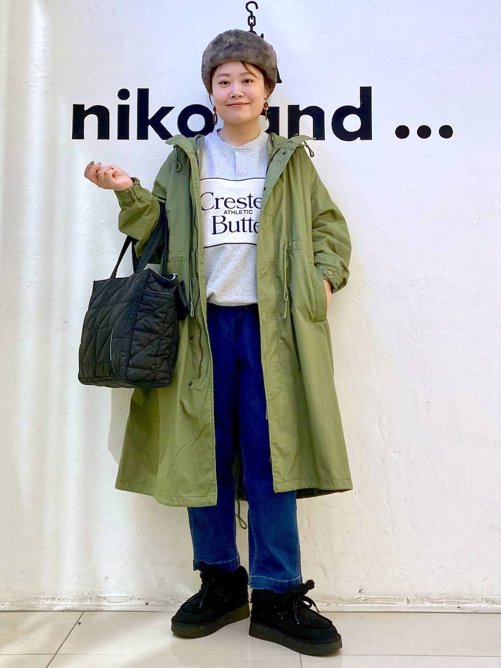 グリーン系のモッズコート、ブルー系のその他パンツ、ブラック系のトートバッグを着用したレディースの冬コーディネートの2枚目の写真