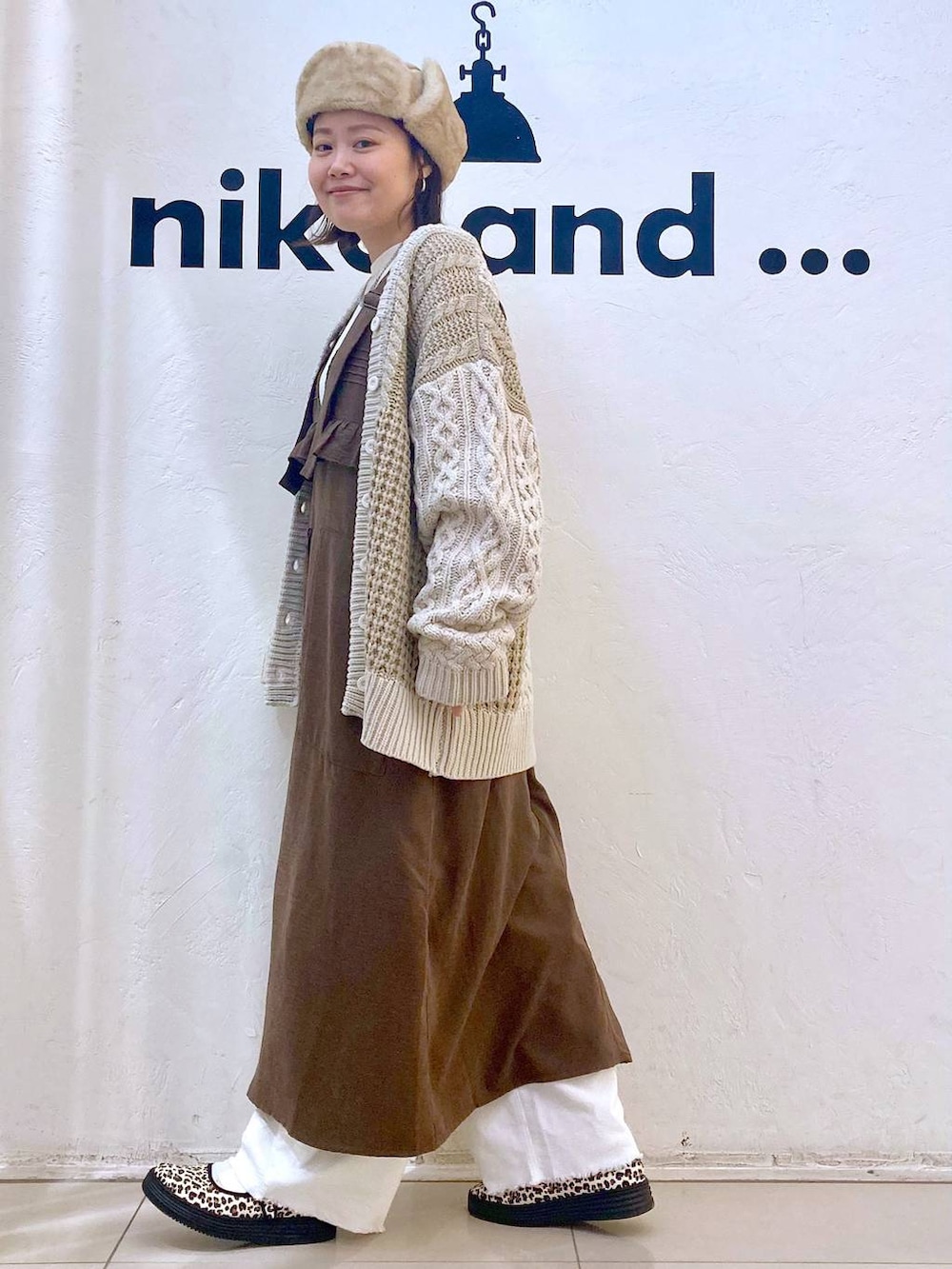 ホワイト系のその他パンツ、その他のスニーカー、ブラウン系のジャンパースカートを着用したレディースの冬コーディネートの3枚目の写真