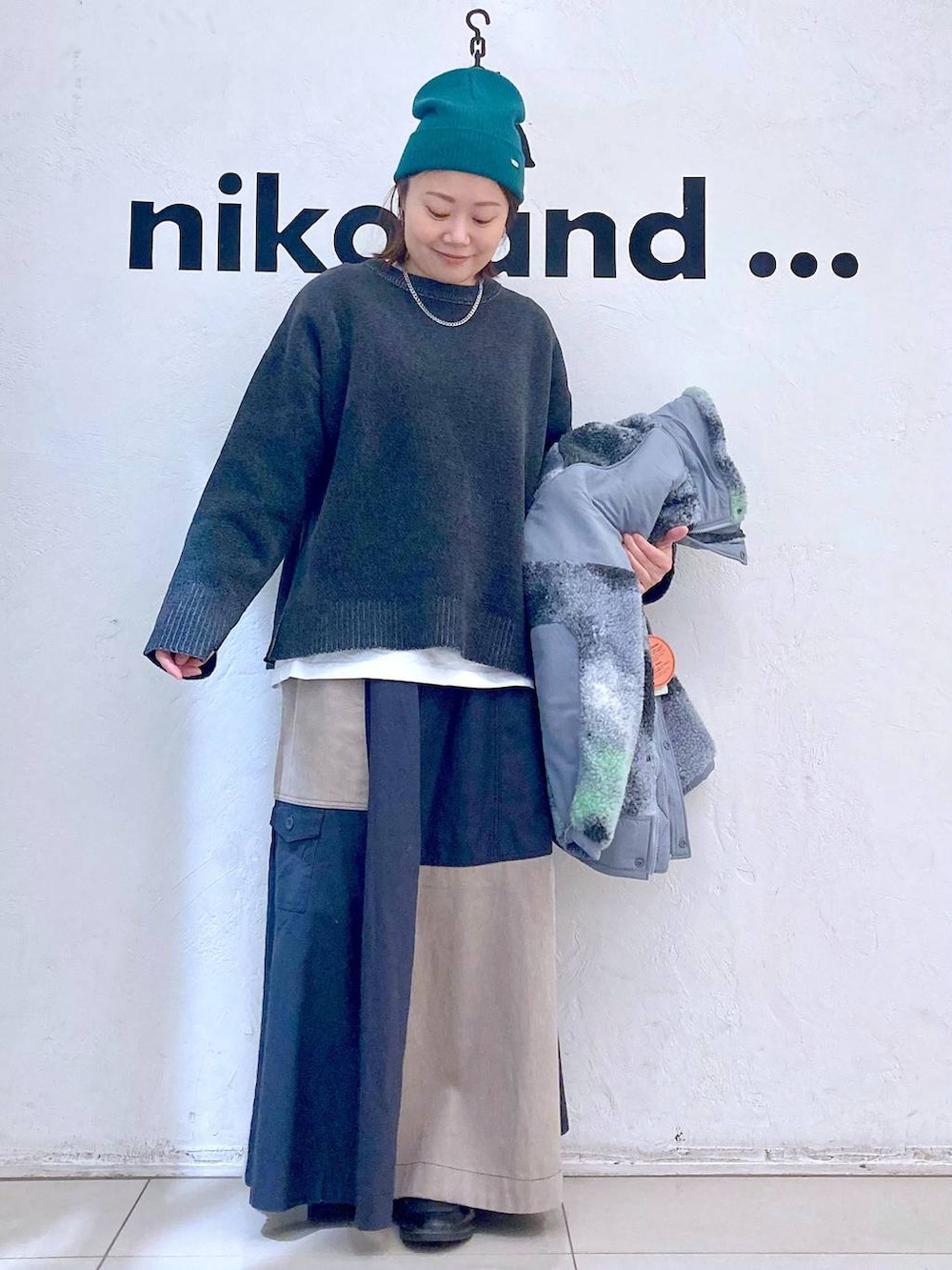 グレー系のブルゾン、ホワイト系のTシャツ/カットソー、グレー系のニット/セーターを着用したレディースの冬コーディネートの2枚目の写真