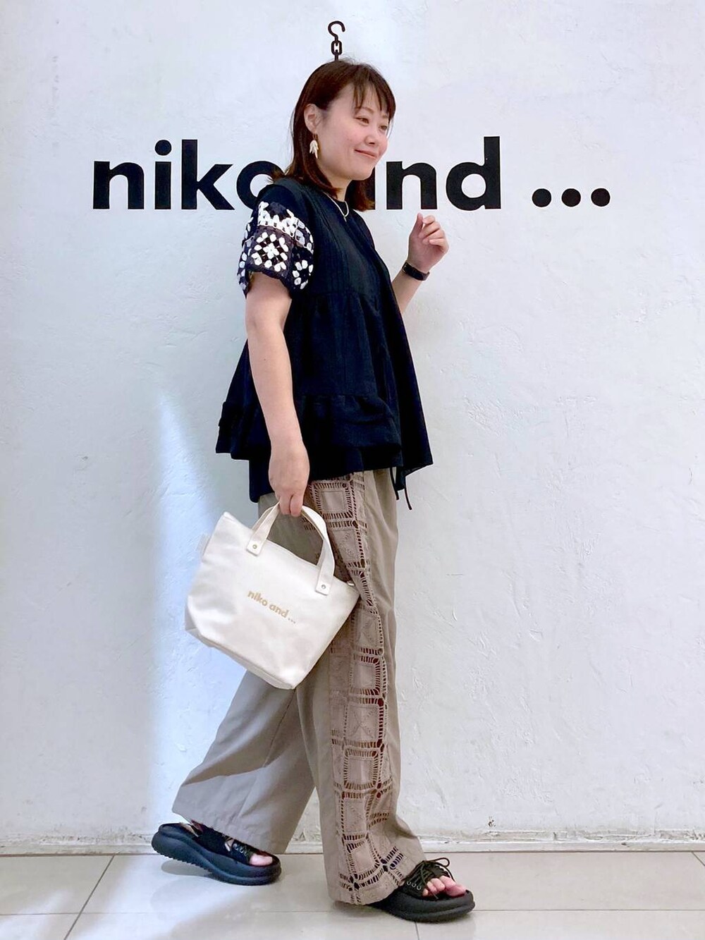 ホワイト系のトートバッグ、ブラウン系のその他パンツ、ブラック系のベストを着用したレディースの夏コーディネートの5枚目の写真