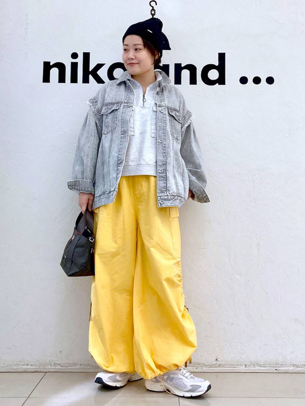 ベージュ系のスウェット、グレー系のデニムジャケット、ホワイト系のスニーカーを着用したレディースの冬コーディネートの2枚目の写真