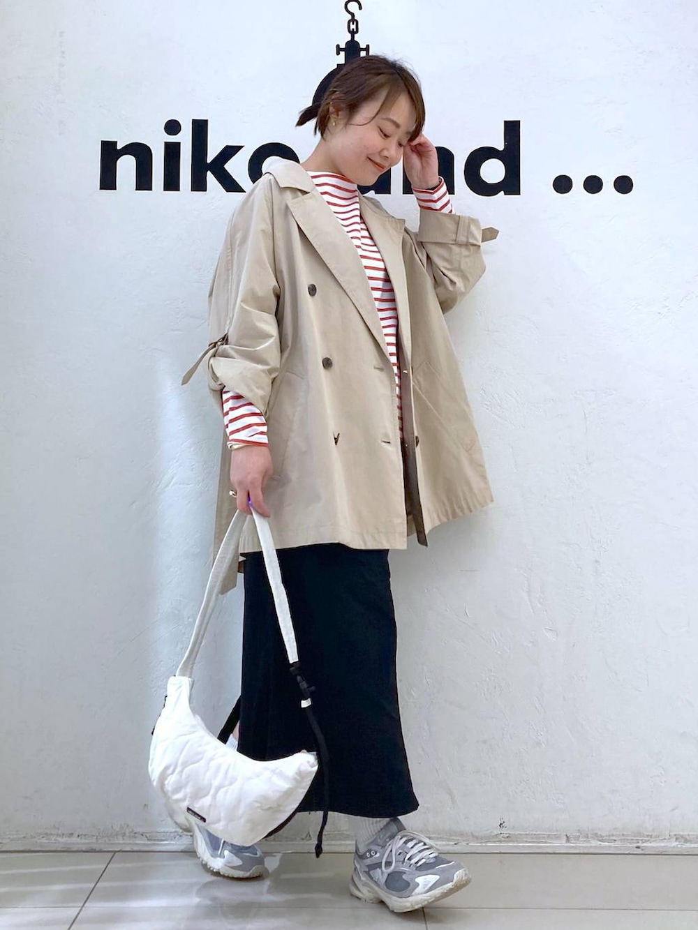 ベージュ系のトレンチコート、ベージュ系のショルダーバッグ、ブラック系のスカートを着用したレディースの春コーディネートの3枚目の写真