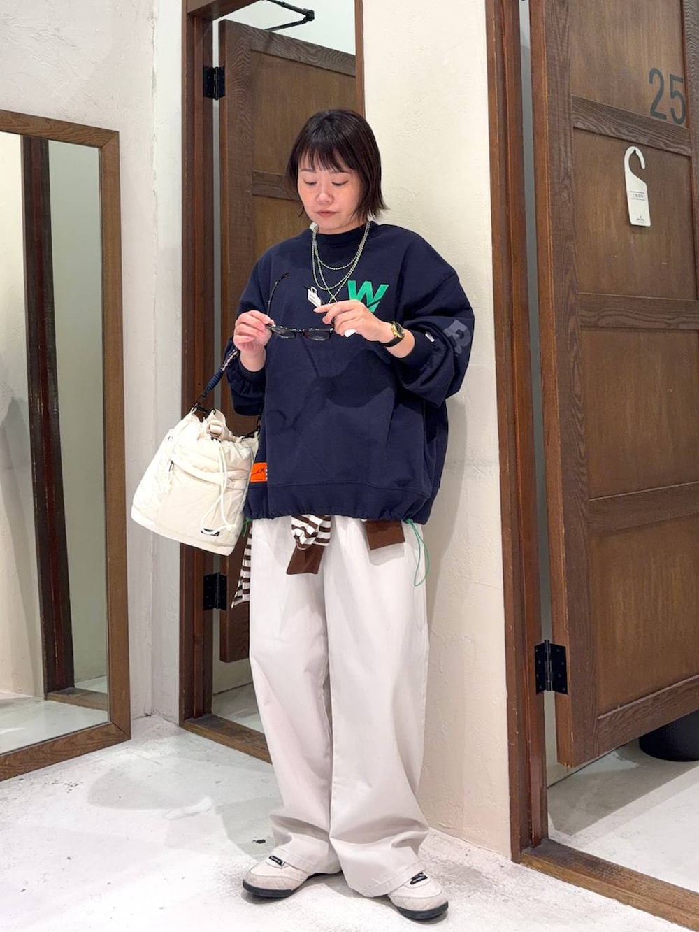 ベージュ系のチノパンツ、ベージュ系のショルダーバッグ、ブラウン系のサングラスを着用したレディースの冬コーディネートの4枚目の写真