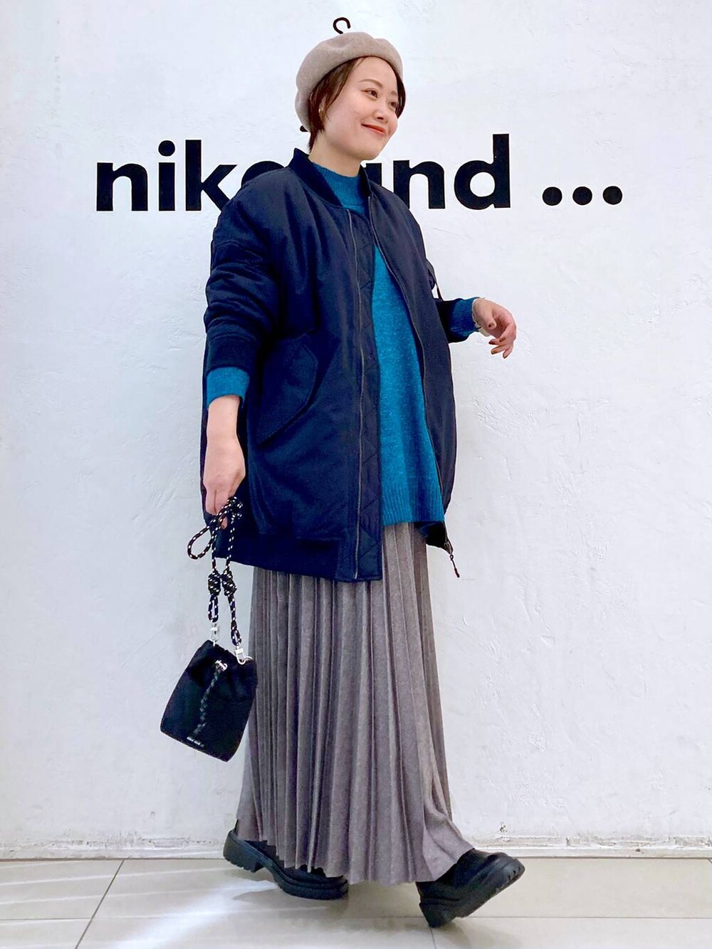 ブラック系のMA-1、グリーン系のニット/セーター、ブラック系のブーツを着用したレディースの冬コーディネートの4枚目の写真