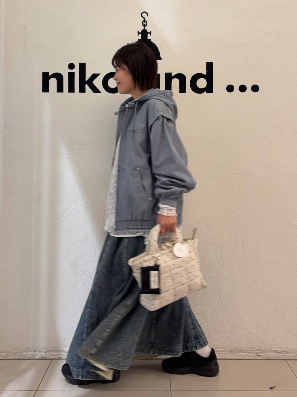 ブルー系のスカート、ホワイト系のトートバッグ、ブルー系のブルゾンを着用したレディースの冬コーディネートの3枚目の写真