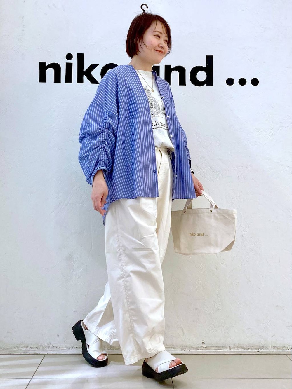 ホワイト系のサンダル、ベージュ系のTシャツ/カットソー、ホワイト系のトートバッグを着用したレディースの春コーディネートの3枚目の写真