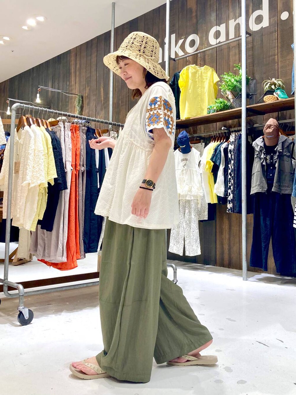 ホワイト系のベスト、ベージュ系のサンダル、グレー系のかごバッグを着用したレディースの夏コーディネートの3枚目の写真