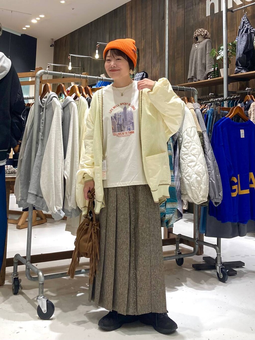 ブラウン系のスカート、ブラウン系のショルダーバッグ、ホワイト系のTシャツ/カットソーを着用したレディースの秋コーディネートの2枚目の写真