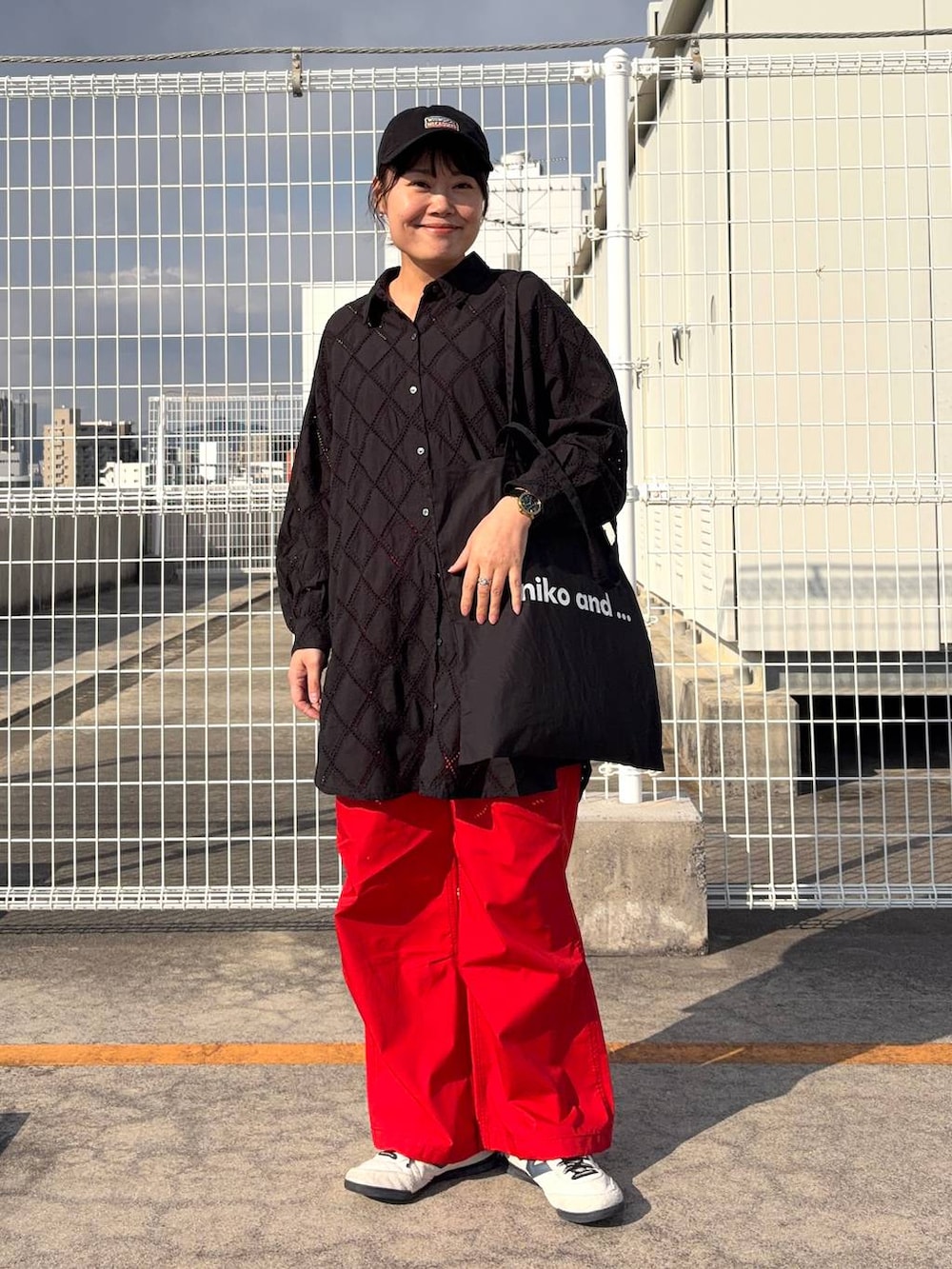 ブラック系のトートバッグ、ブラック系のチュニック、オレンジ系のその他パンツを着用したレディースの春コーディネートの2枚目の写真