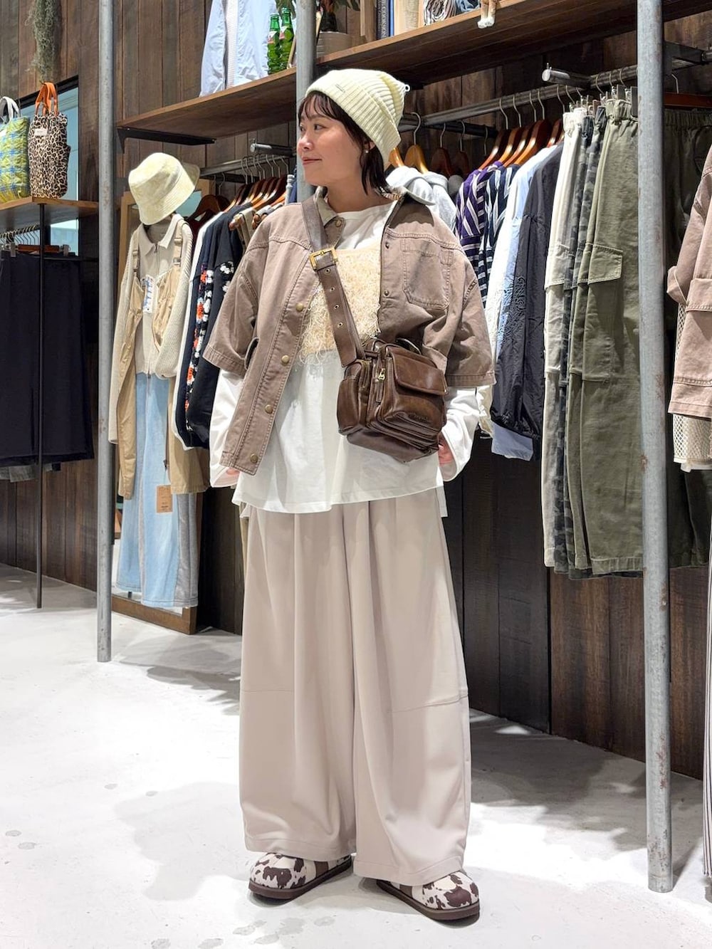 ブラウン系のショルダーバッグ、ベージュ系のベスト、ホワイト系のTシャツ/カットソーを着用したレディースの春コーディネートの2枚目の写真