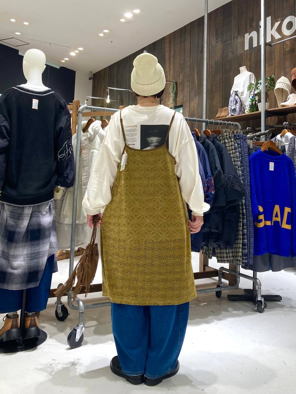 ブルー系のデニムパンツ、ブラウン系のショルダーバッグ、イエロー系のワンピースを着用したレディースの秋コーディネートの4枚目の写真