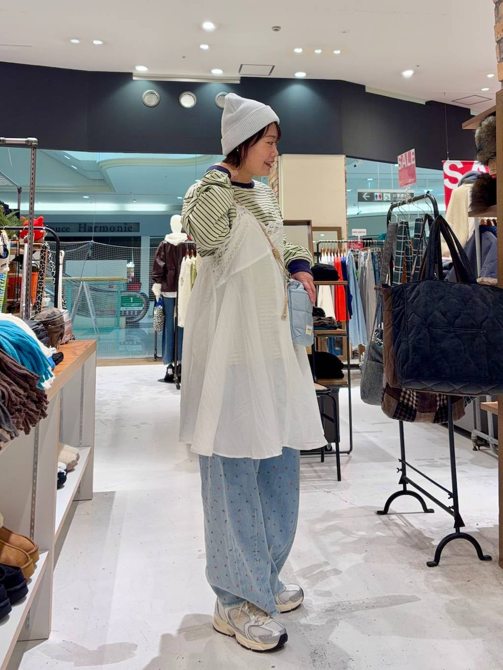 ホワイト系のスニーカー、ブルー系のショルダーバッグ、ブルー系のデニムパンツを着用したレディースの冬コーディネートの4枚目の写真