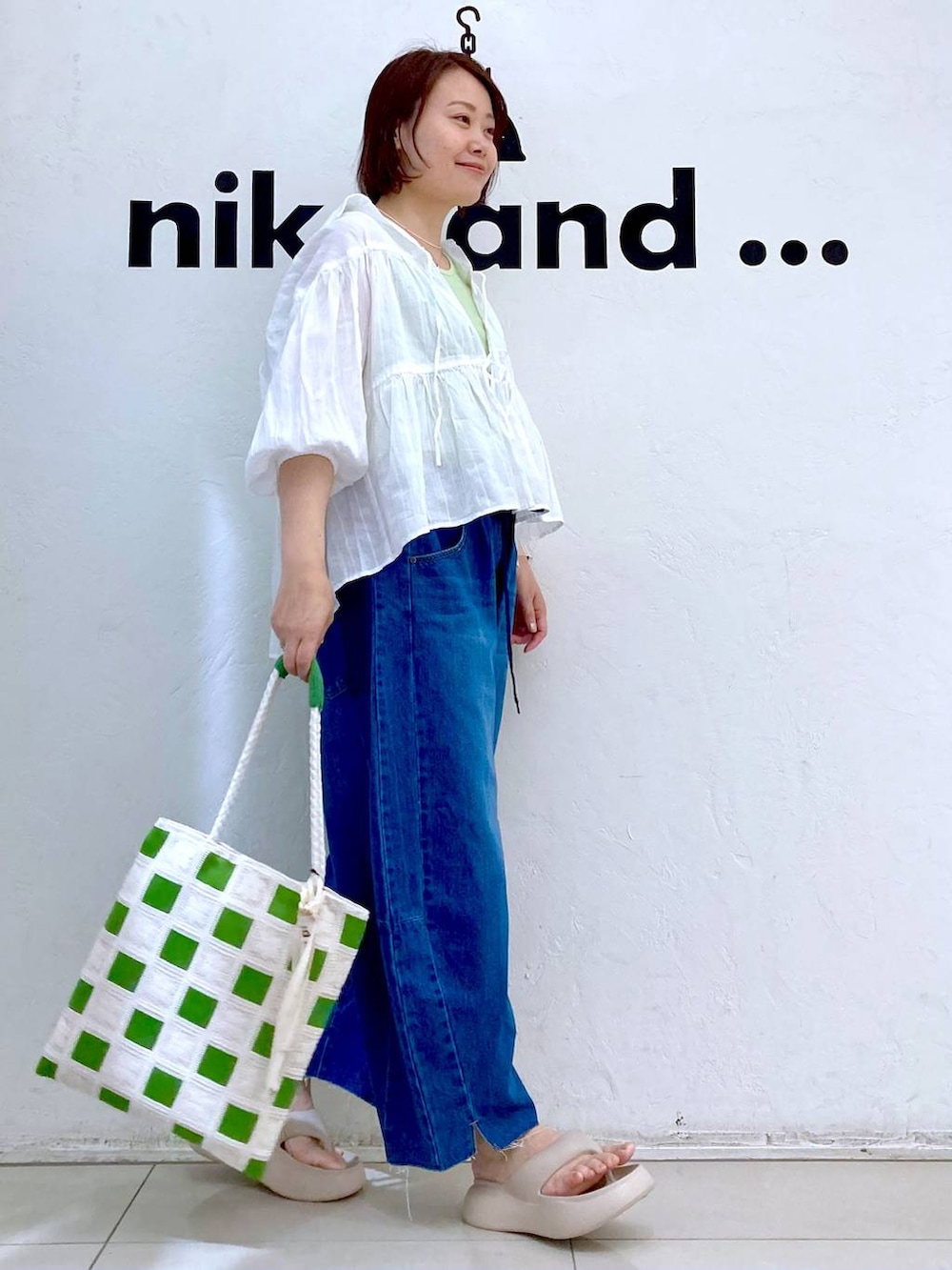 ベージュ系のサンダル、ブルー系のデニムパンツ、グリーン系のタンクトップを着用したレディースの夏コーディネートの3枚目の写真