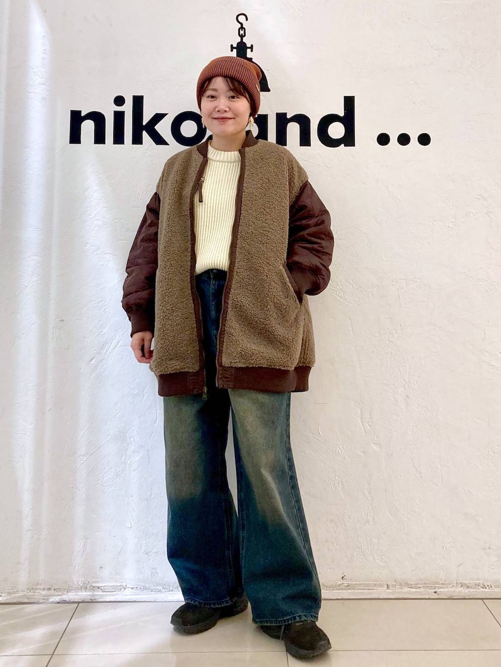 レッド系のMA-1、ベージュ系のニット/セーター、オレンジ系のニットキャップ/ビーニーを着用したレディースの秋コーディネートの2枚目の写真