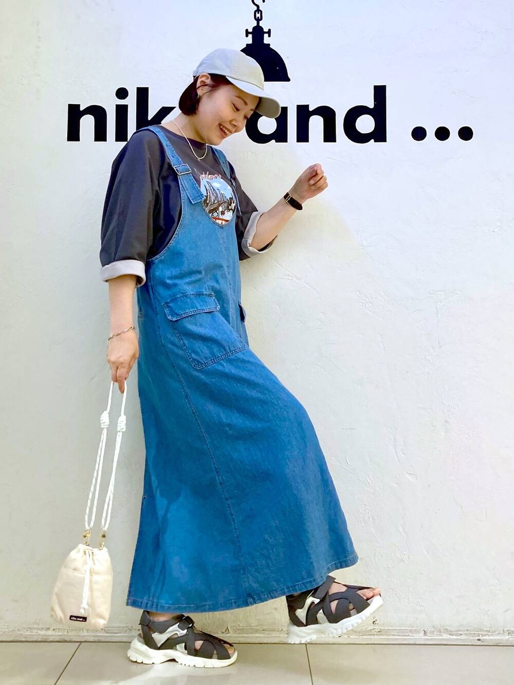 ホワイト系のショルダーバッグ、グレー系のTシャツ/カットソー、ブルー系のジャンパースカートを着用したレディースの夏コーディネートの3枚目の写真