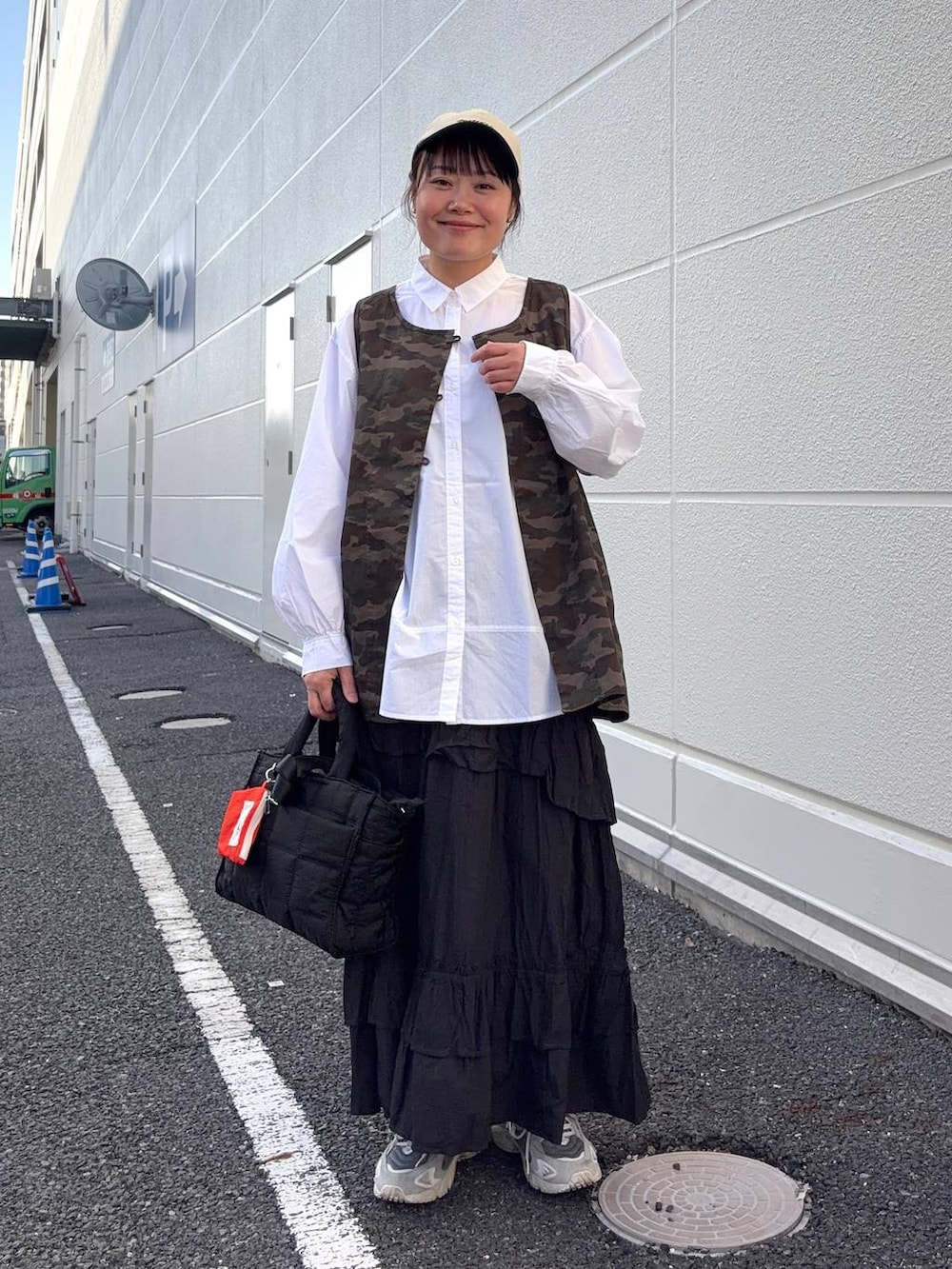 ブラック系のトートバッグ、ブラウン系のベスト、ホワイト系のシャツ/ブラウスを着用したレディースの春コーディネートの2枚目の写真