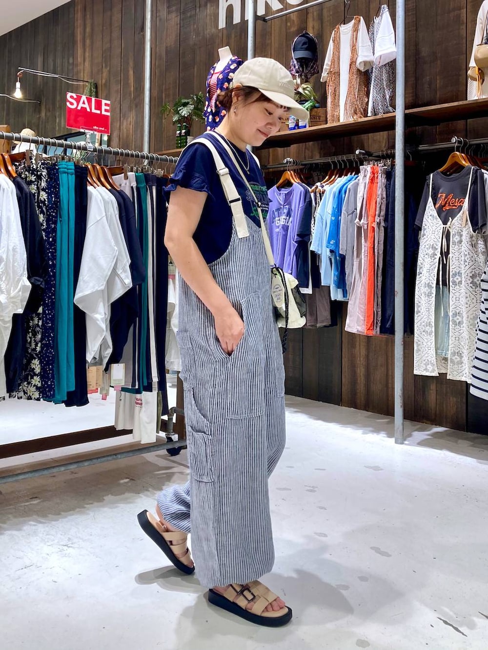 ブルー系のサロペット/オーバーオール、ブルー系のTシャツ/カットソー、ベージュ系のショルダーバッグを着用したレディースの夏コーディネートの5枚目の写真