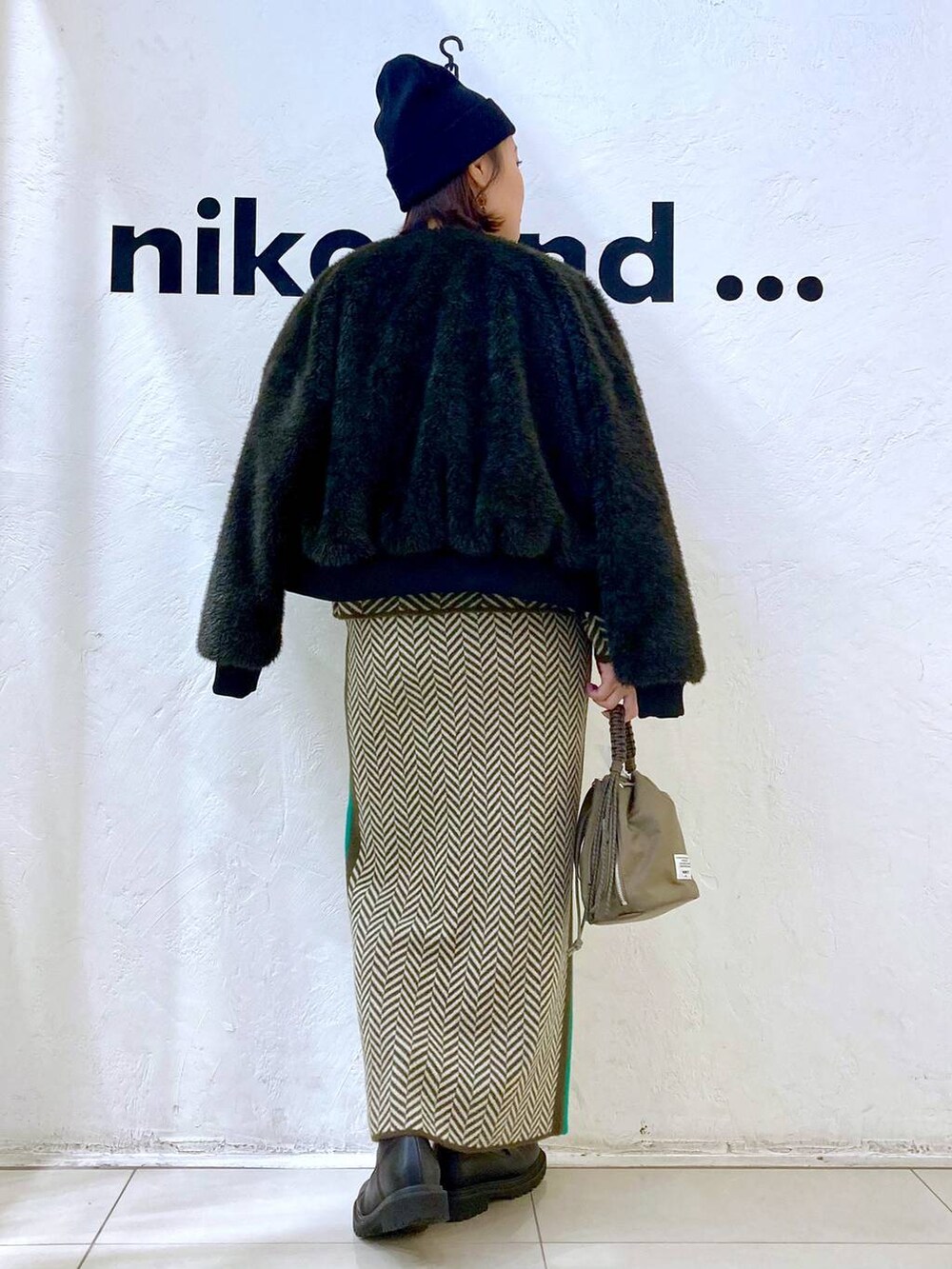グレー系のブルゾン、グリーン系のショルダーバッグ、ブラウン系のスカートを着用したレディースの冬コーディネートの4枚目の写真