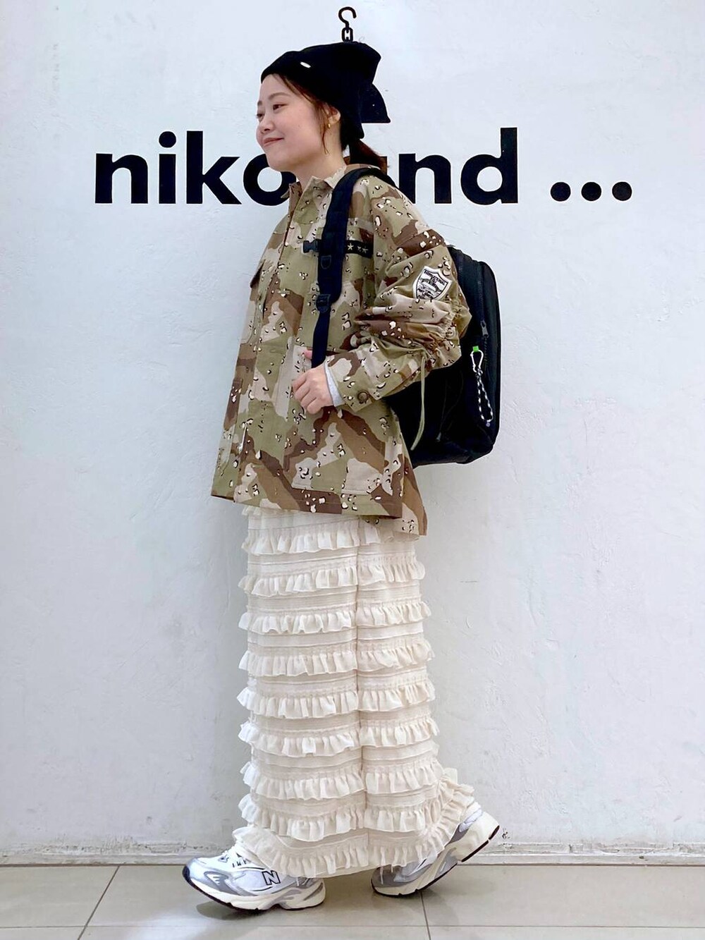 グレー系のスニーカー、ベージュ系のスカート、グレー系のバックパック/リュックを着用したレディースの秋コーディネートの3枚目の写真