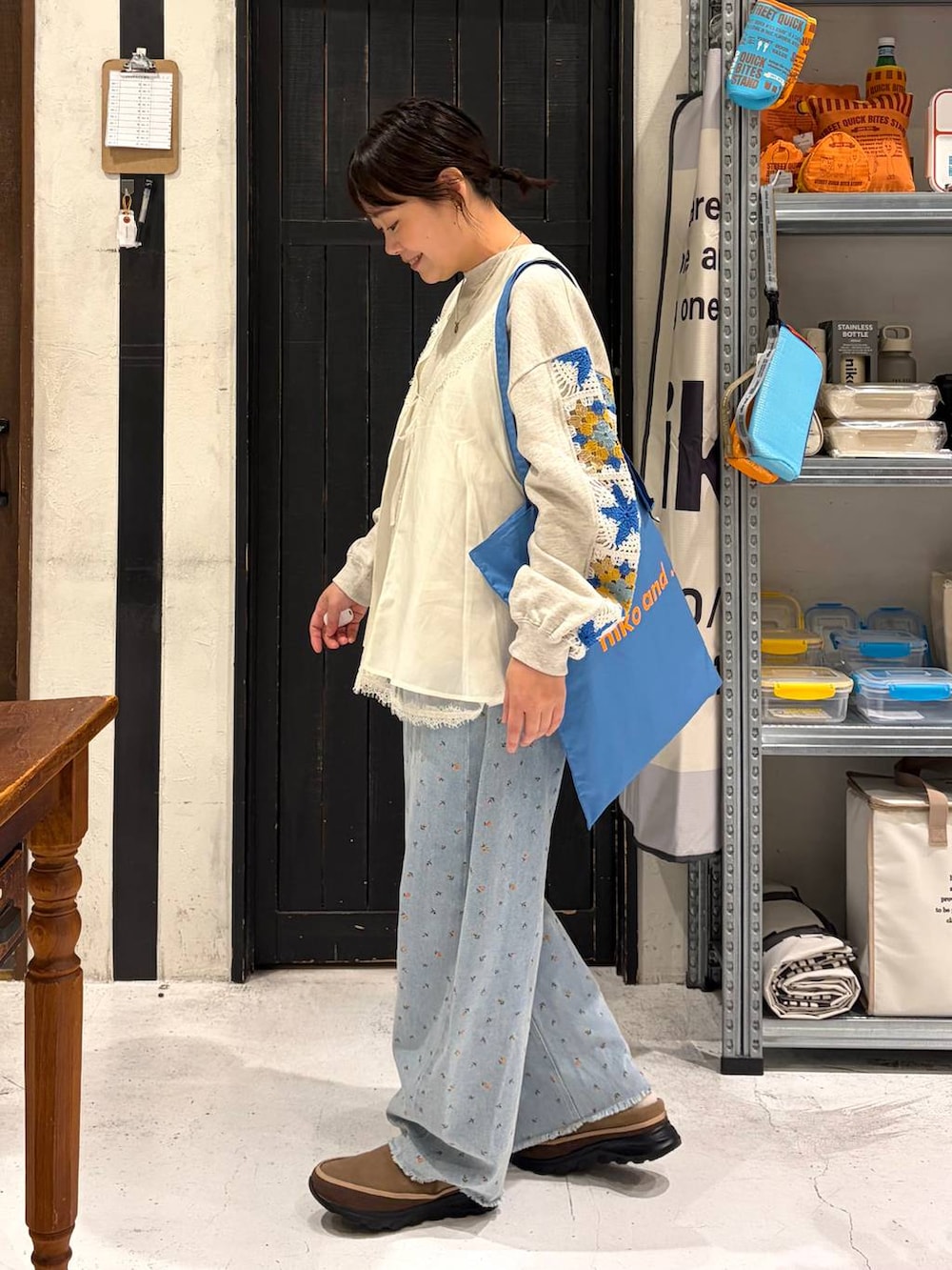 ベージュ系のスウェット、ブルー系のトートバッグ、ブルー系のデニムパンツを着用したレディースの春コーディネートの3枚目の写真