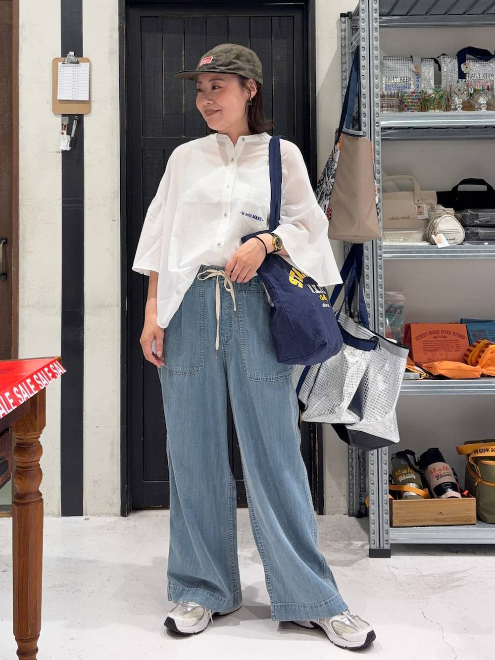 ブルー系のトートバッグ、ブルー系のデニムパンツ、その他のキャップを着用したレディースの夏コーディネートの2枚目の写真