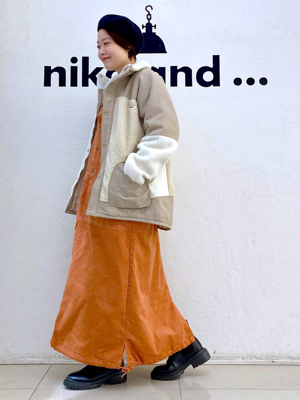 ベージュ系のその他アウター、ホワイト系のニット/セーター、ブラック系のブーツを着用したレディースの冬コーディネートの2枚目の写真