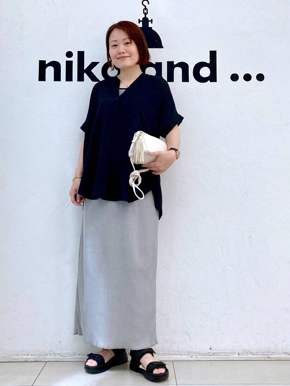 ブラック系のサンダル、ホワイト系のタンクトップ、ブラウン系のショルダーバッグを着用したレディースの夏コーディネートの2枚目の写真