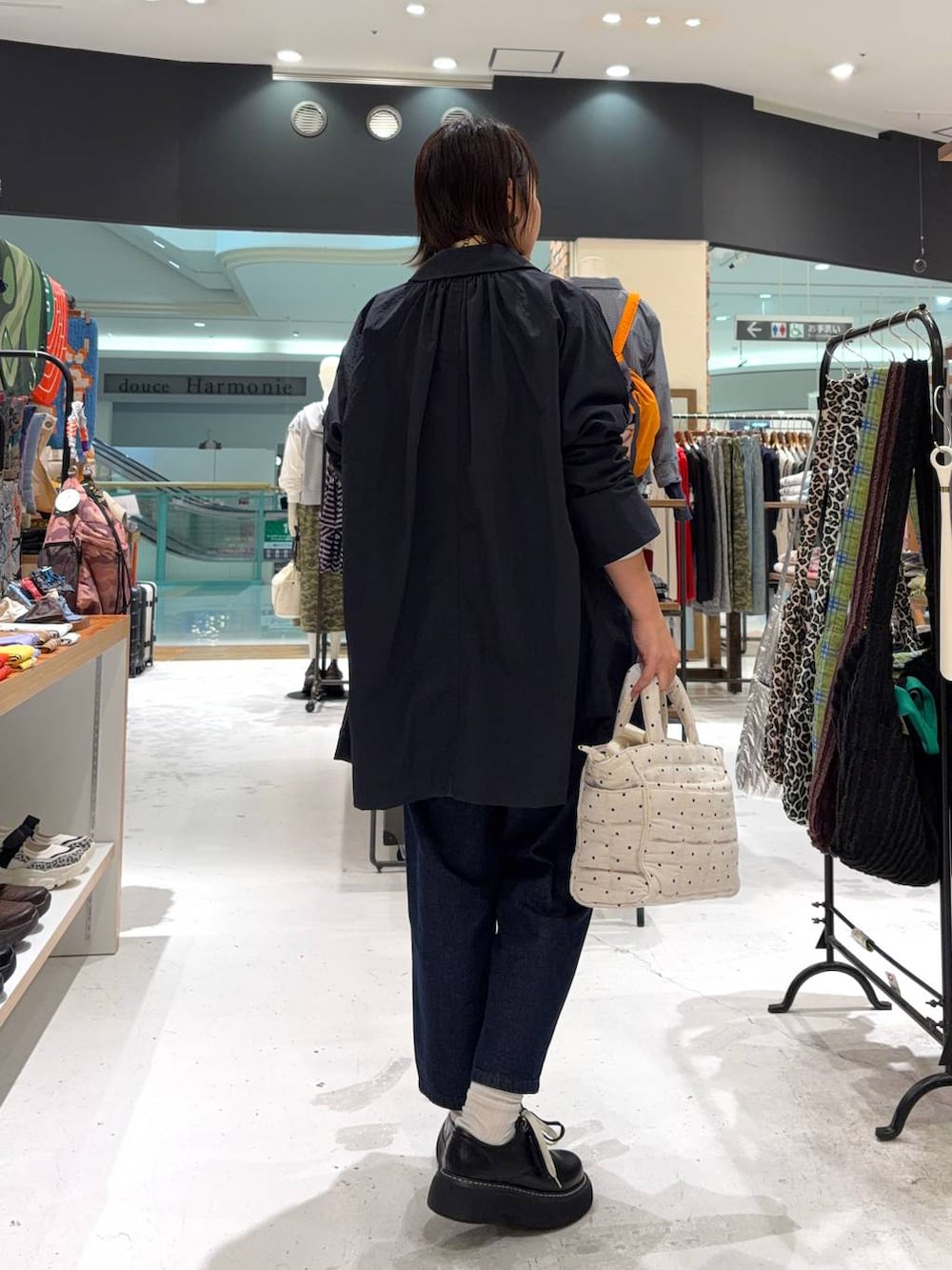 ブラック系のその他シューズ、ホワイト系のトートバッグ、ブルー系のステンカラーコートを着用したレディースの春コーディネートの5枚目の写真