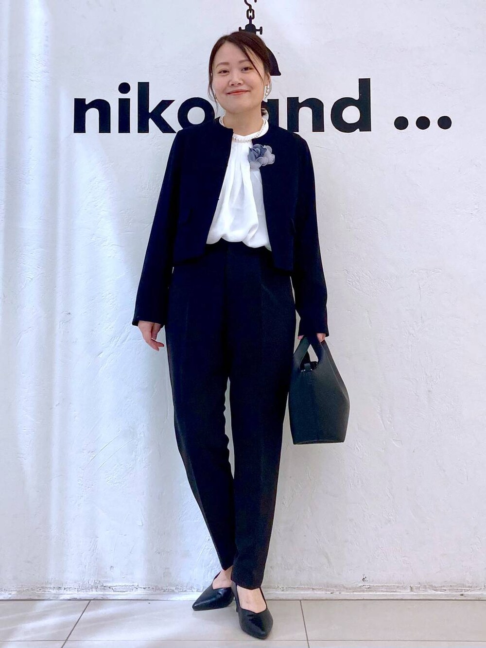 ブラック系のスーツパンツ、ホワイト系のシャツ/ブラウス、ブラック系のノーカラージャケットを着用したレディースの冬コーディネートの2枚目の写真