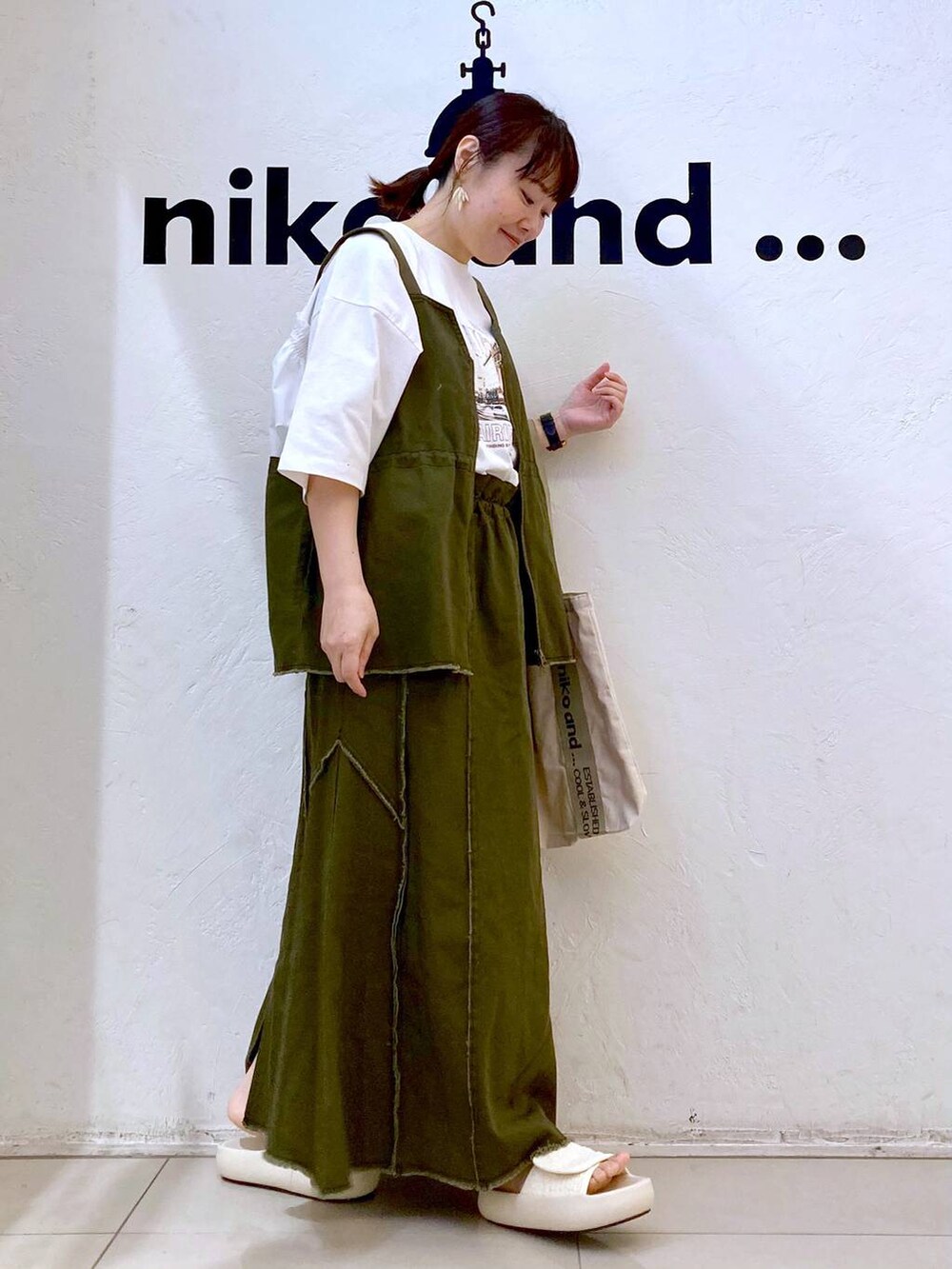 ベージュ系のトートバッグ、ベージュ系のサンダル、ホワイト系のTシャツ/カットソーを着用したレディースの春コーディネートの5枚目の写真