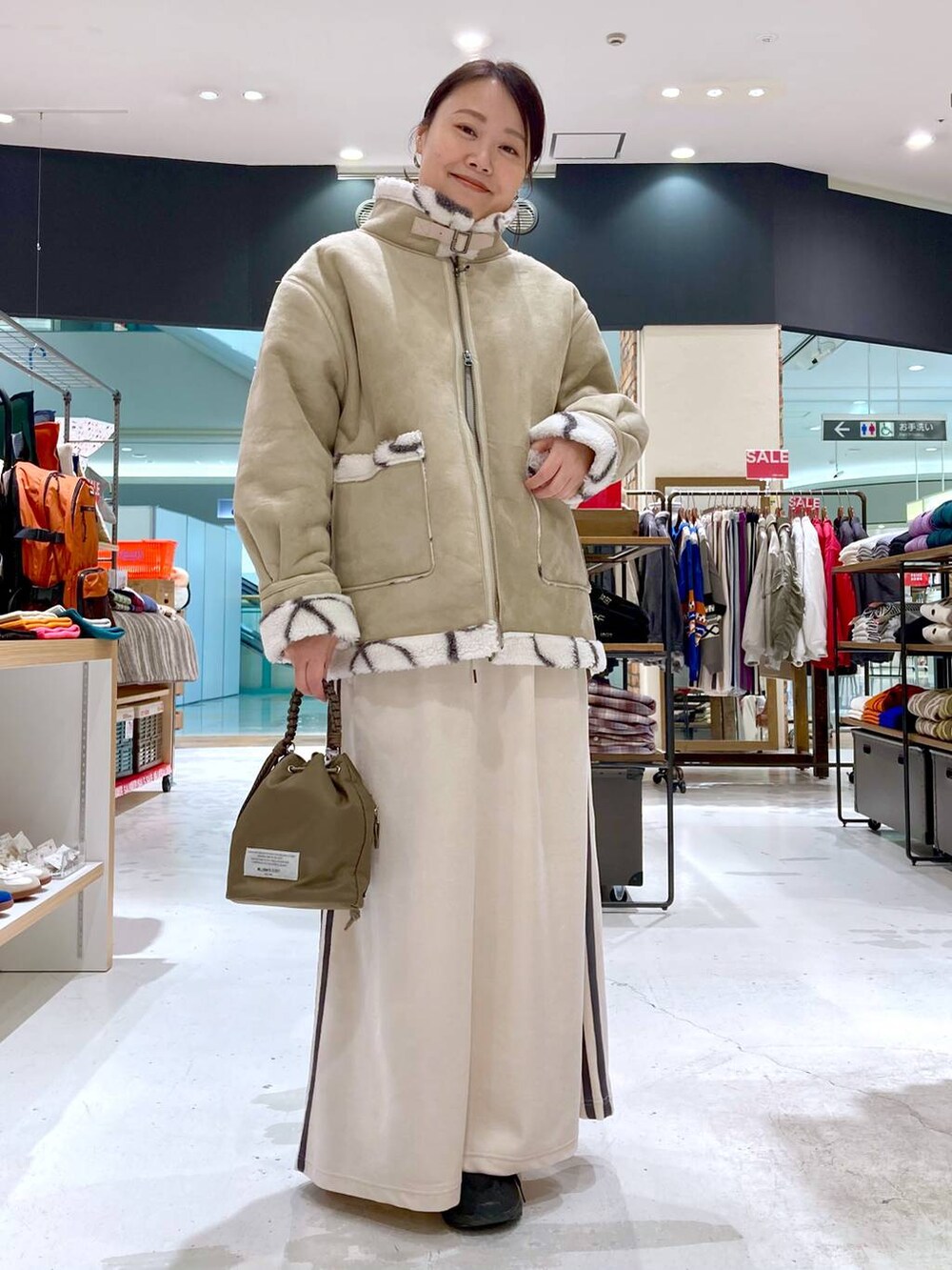 ベージュ系のニット/セーター、グリーン系のショルダーバッグ、ベージュ系のムートンコートを着用したレディースの冬コーディネートの2枚目の写真