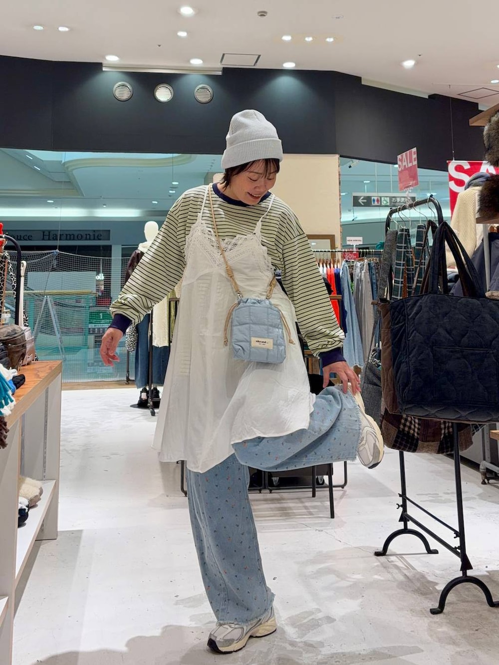 ホワイト系のスニーカー、ブルー系のショルダーバッグ、ブルー系のデニムパンツを着用したレディースの冬コーディネートの5枚目の写真