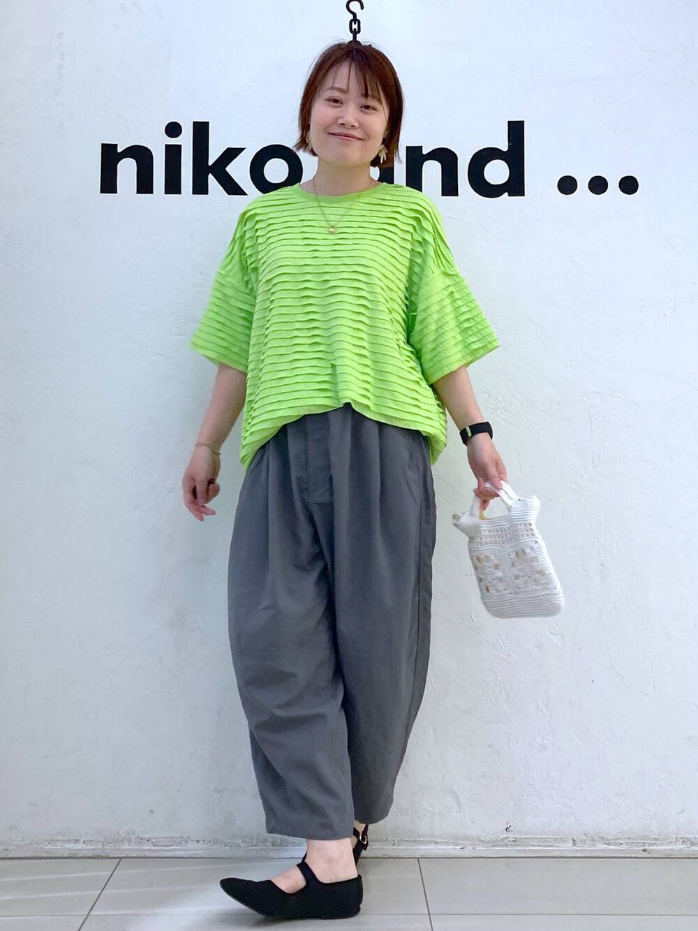 ホワイト系のショルダーバッグ、グリーン系のTシャツ/カットソー、グレー系のその他パンツを着用したレディースの春コーディネートの2枚目の写真