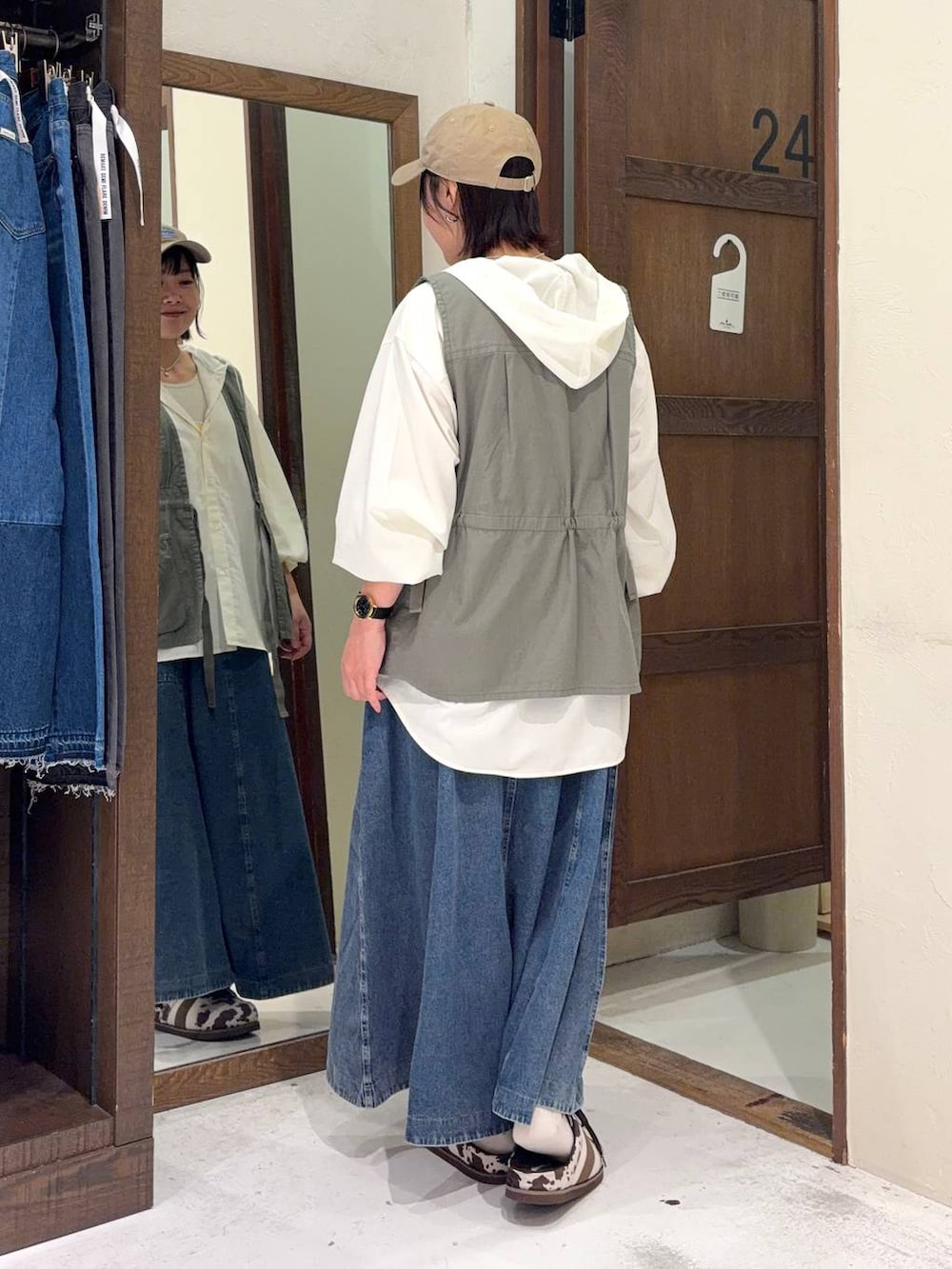 ブルー系のスカート、グリーン系のベスト、ホワイト系のシャツ/ブラウスを着用したレディースの春コーディネートの3枚目の写真