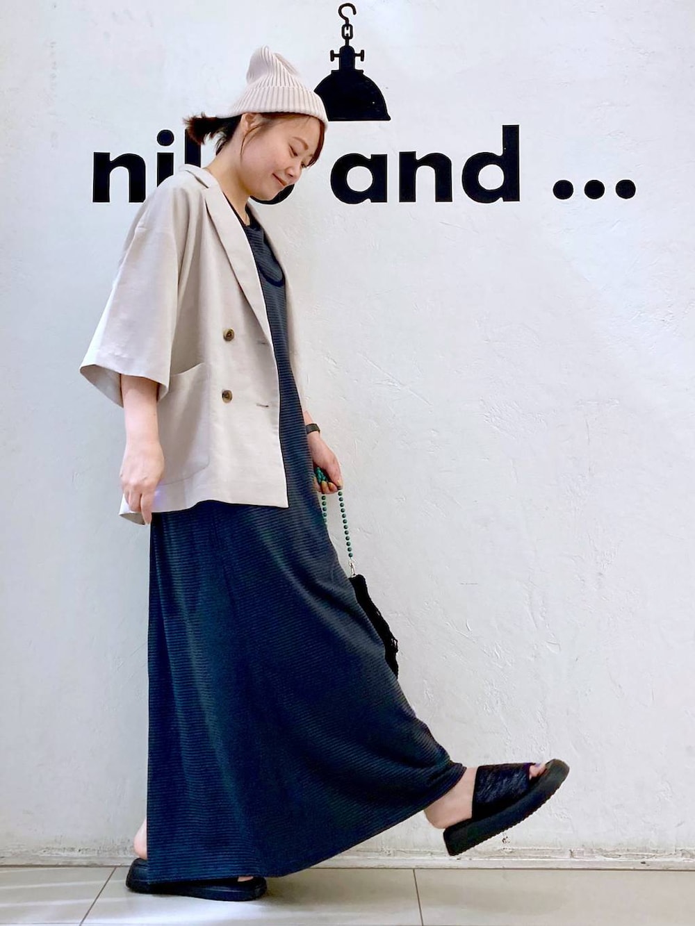 ブラック系のショルダーバッグ、ベージュ系のテーラードジャケット、ブラック系のサンダルを着用したレディースの夏コーディネートの4枚目の写真