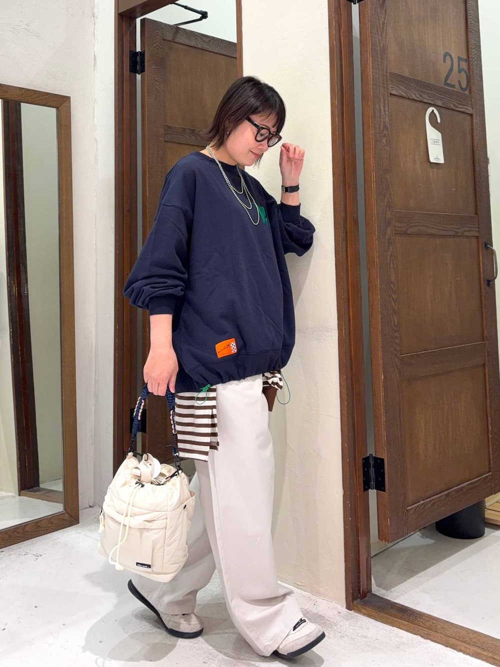 ベージュ系のチノパンツ、ベージュ系のショルダーバッグ、ブラウン系のサングラスを着用したレディースの冬コーディネートの2枚目の写真