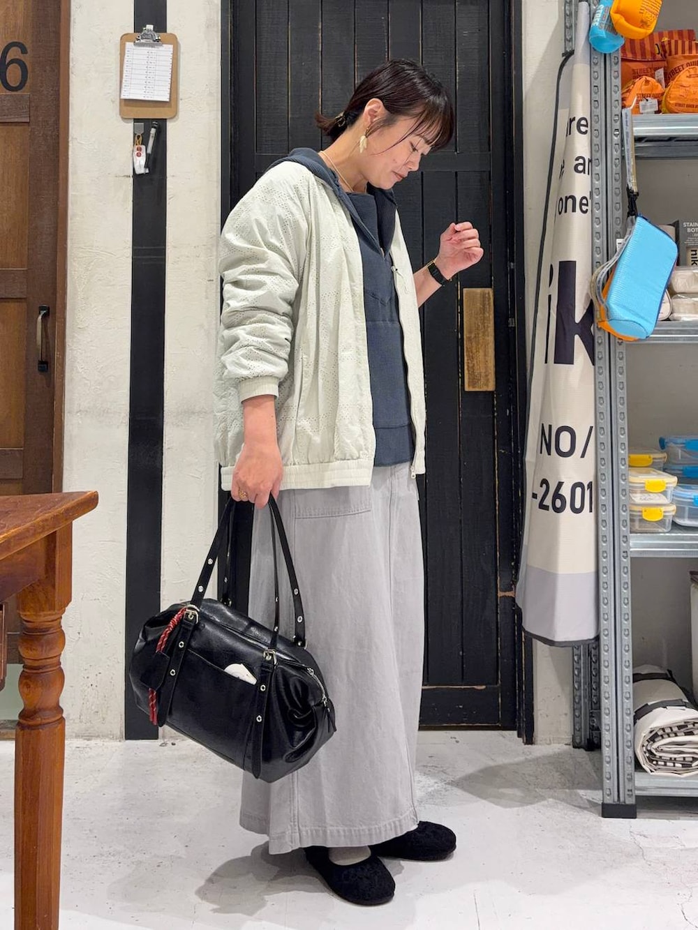 グレー系のスカート、ブラック系のパンプス、ホワイト系のブルゾンを着用したレディースの春コーディネートの5枚目の写真