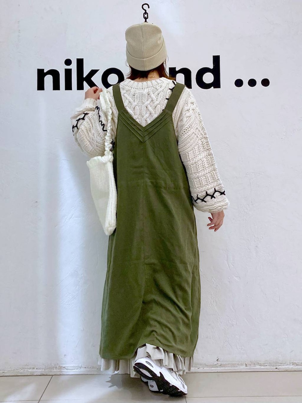 グリーン系のジャンパースカート、ベージュ系のショルダーバッグ、ベージュ系のニット/セーターを着用したレディースの冬コーディネートの4枚目の写真