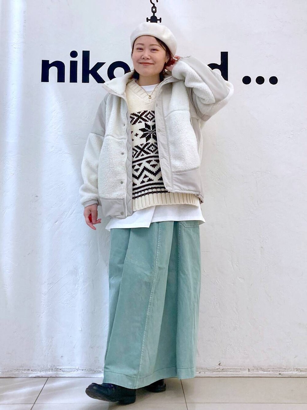 ベージュ系のベスト、ベージュ系のブルゾン、グリーン系のスカートを着用したレディースの冬コーディネートの2枚目の写真